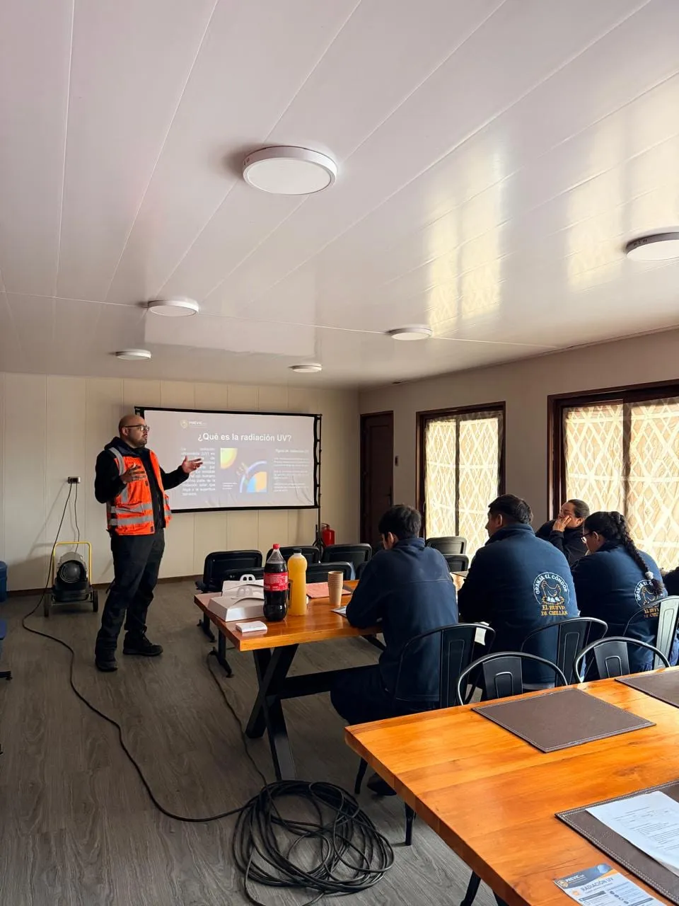 Relator de Previc dictando una capacitación de seguridad laboral en sala, con presentación proyectada y equipo de trabajo atento
