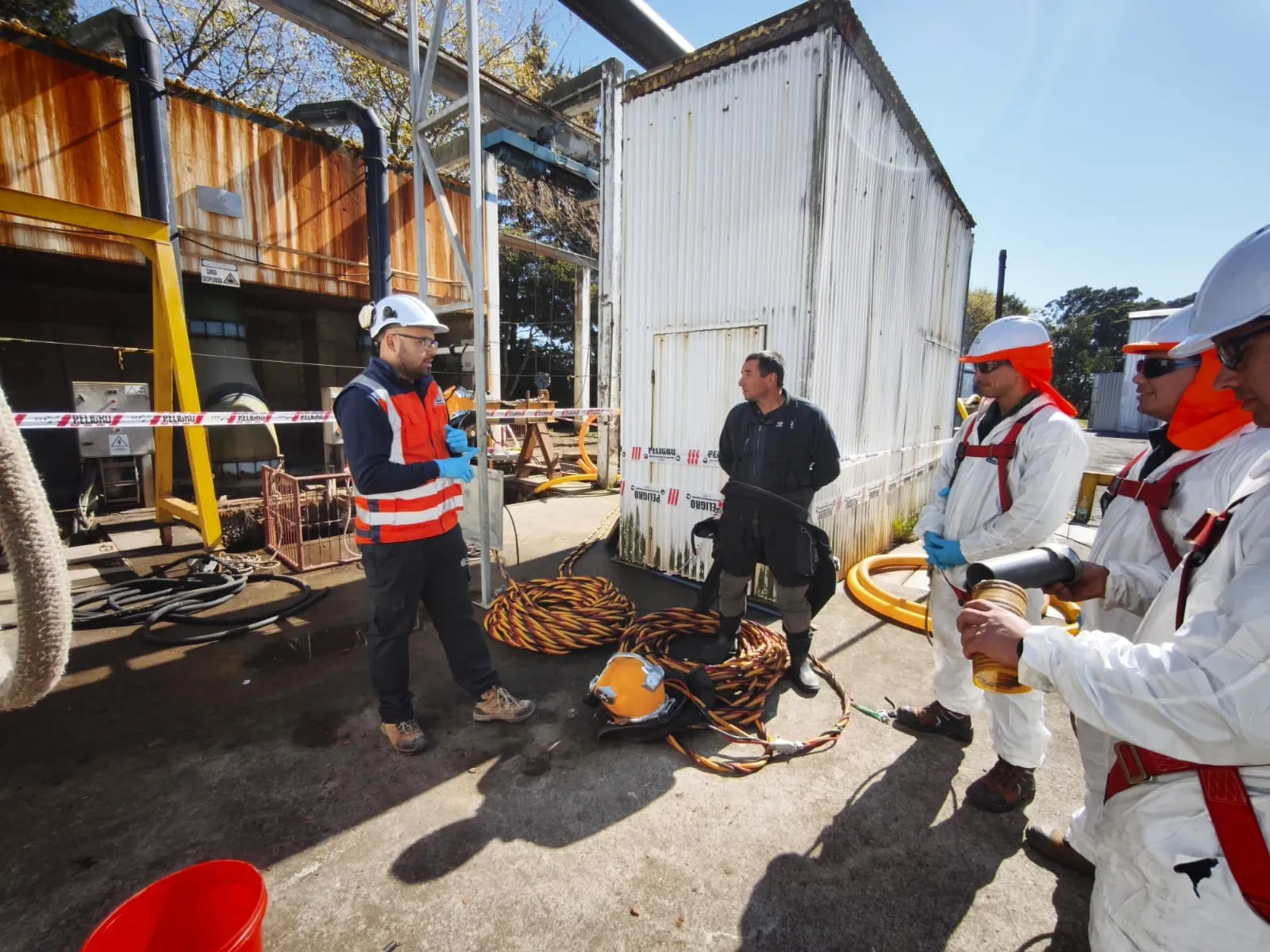 Asesor de Previc instruyendo a una cuadrilla con trajes y equipos de buceo industrial antes de entrar a una faena en espacios confinados